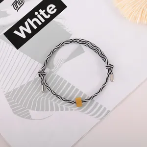 Black and white striped braided cord bracelet with gold metal accent for daily wear.