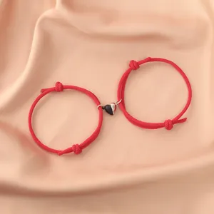 Close-up detail of stylish black and white magnetic heart couple rope bracelets set.