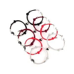 Close-up detail of braided couple bracelets featuring magnetic Yin-Yang charms and metal clasps.