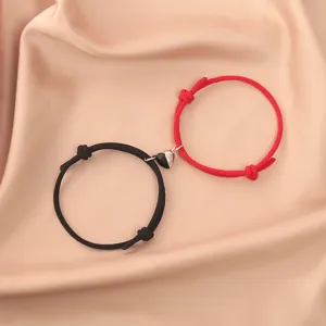 Matching couple magnetic bracelets with black and red woven ropes and a cute heart charm.