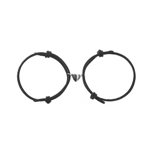Close up detail of matching black braided rope couple bracelets with magnetic split heart pendants.