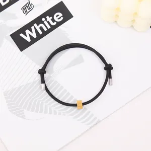 Detail view of the black woven rope bracelet with metal charms, simple and stylish design.