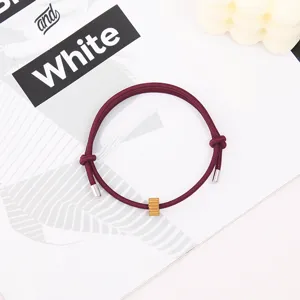 Minimalist burgundy rope bracelet with metallic tips and a golden gear bead for daily wear.