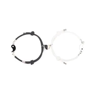 Detailed shot of black and white braided couple bracelets with magnetic heart and yin-yang charms.