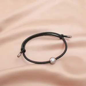 Detailed close-up of minimalist black cord survival bracelet featuring a sleek metal bead and caps.