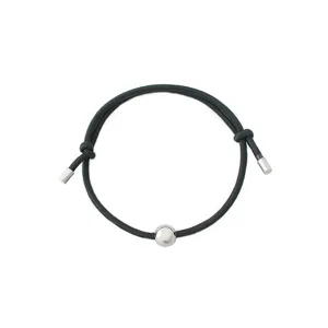 Detailed shot of minimalist black cord bracelet featuring a sleek central metal bead and tips.