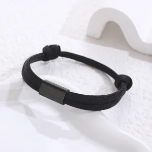 Black woven paracord bracelet detail shot, stainless steel tube, minimalist unisex jewelry.