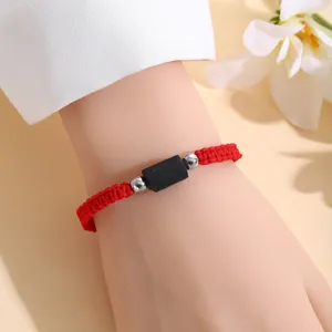 Vista di dettaglio del bracciale regolabile intrecciato in tormalina nera e corda rossa.