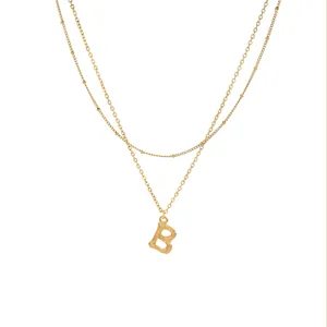 Dettaglio collana a catena a doppio strato d'oro con ciondolo lettera B gioielli da donna