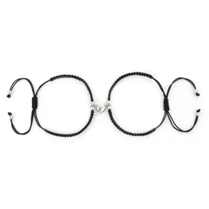 Primo piano dettagliato di bracciali di coppia intrecciati neri con chiusura magnetica a cuore.