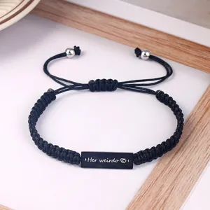 Handmade braided black cord couple bracelet detail shot with engraved metal plate.