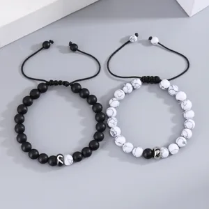 Primo piano di bracciali di perle di coppia con perle opache nere e marmo bianco.
