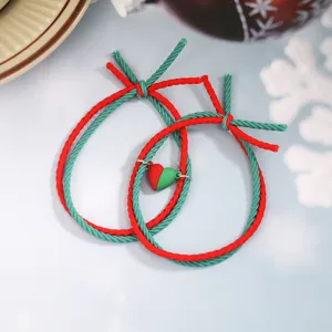 Gros plan detail du bracelet de couple tisse rouge et vert avec pendentif coeur magnetique.