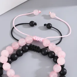 Primo piano dettagliato di bracciali di coppia con perle di quarzo rosa e perle nere.