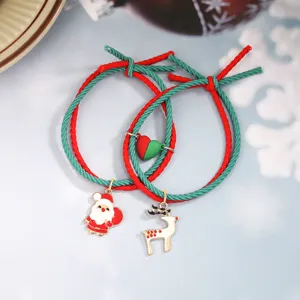 Détail en gros plan de bracelets de couple de Noël tressés rouges et verts avec pendentif.