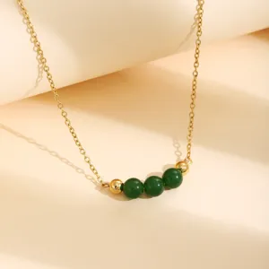 Vue détaillée du collier chaîne doré avec des perles vertes élégantes et des intercalaires.