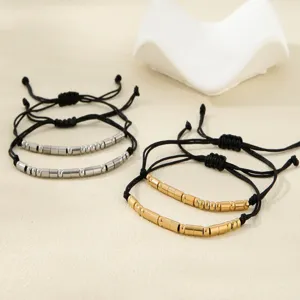 Morse code couple bracelet detail showing gold and silver metal beads on black cord.