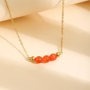 Gros plan détaillé du collier de chaîne doré élégant avec des perles d'œil de chat oranges.