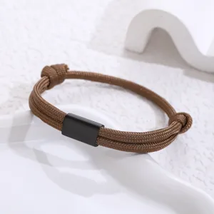 Close-up detail of a brown paracord braided bracelet featuring a sleek black stainless steel tube.