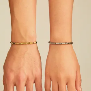 Stainless steel Morse code couple bracelets in gold and silver, elegant wrist detail view.