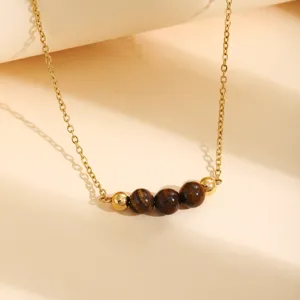 Vue détaillée du collier de chaîne dorée avec des perles de pierres précieuses et métaux.