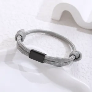 Close-up detail of grey paracord braided bracelet with black metal tube accent, fine weave texture.