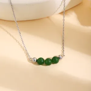 Gros plan détaillé du collier argenté élégant avec trois perles vert foncé et des accents métalliques.