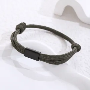 Close-up detail shot of a military green paracord bracelet with a sleek black metal tube.