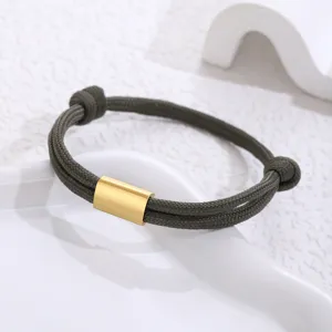 Close-up of the green paracord bracelet featuring a polished gold stainless steel tube detail.