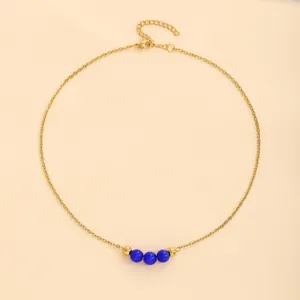 Vue détaillée de collier en chaîne dorée en acier inoxydable avec trois perles œil-de-chat bleu.