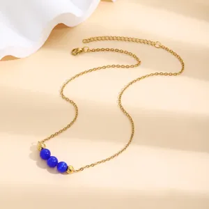 Détail de collier en acier inoxydable doré avec trois perles œil de chat bleues chic.