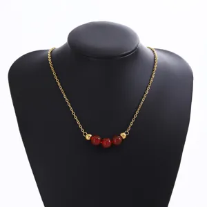 Vue détaillée du collier de mode doré avec trois perles de pierre rouge et finition lisse.