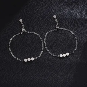 Primo piano dettagliato di bracciali in acciaio inossidabile con ciondoli BFF e catena a maglie.