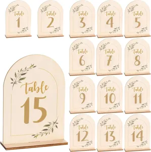 Wooden arch table numbers set with wooden stands and green leaf print for wedding parties.