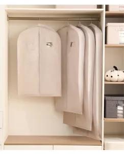 Vue détaillée de housses de protection suspendues pour manteaux et costumes dans l'armoire.