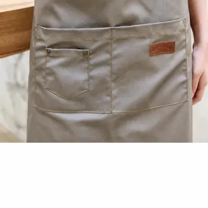 Grembiule da lavoro grigio in tela con tasche per attrezzi e patch in pelle per cucina e bar.