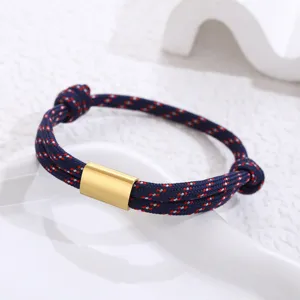 Detailed close-up of blue red woven paracord bracelet featuring a polished gold metal tube.