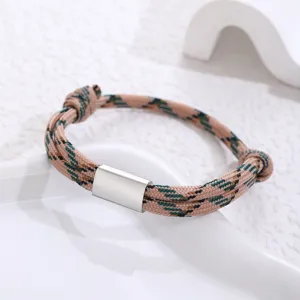 Handmade paracord braided bracelet detail with stainless steel tube and geometric patterned cord.