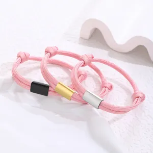 Close-up of pink woven paracord bracelets with black, gold and silver metal tubes details.