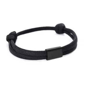 Detail view of a handmade black braided paracord stainless steel bracelet with a smooth metal bar.