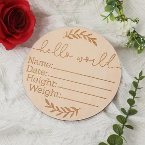 Primo piano di cartolina miliare per neonati in legno con testo inciso e sfondo con decoro floreale.