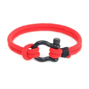 Gros plan détaillé du bracelet en corde rouge tressée doté d'un fermoir manille fer à cheval.
