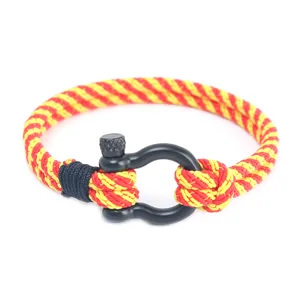 Vue détaillée du bracelet tressé rouge et jaune pour homme avec manille en métal noir.
