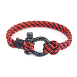 Gros plan détaillé d'un bracelet tressé noir et rouge élégant avec une manille en métal noir.