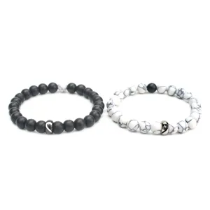 Vista dettagliata di bracciali di coppia abbinati con perle opache nere e bianche.