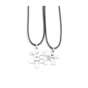 Stainless steel couple puzzle necklace detail view showing engraved pendant and black cord chain.