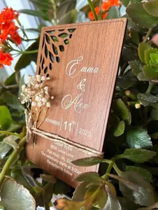 Wooden wedding invitation card detail showing laser cut floral pattern and text engraving.