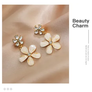 Boucles d'oreilles florales élégantes avec strass scintillants et pétales blancs.