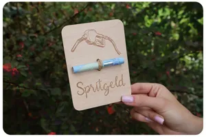 Dettaglio in primo piano della carta regalo in legno con incisione di pistola e corda.
