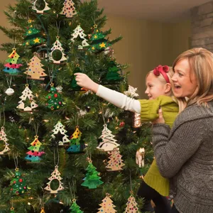 Gros plan d'ornements de sapin de Noël en bois DIY suspendus dans un intérieur.